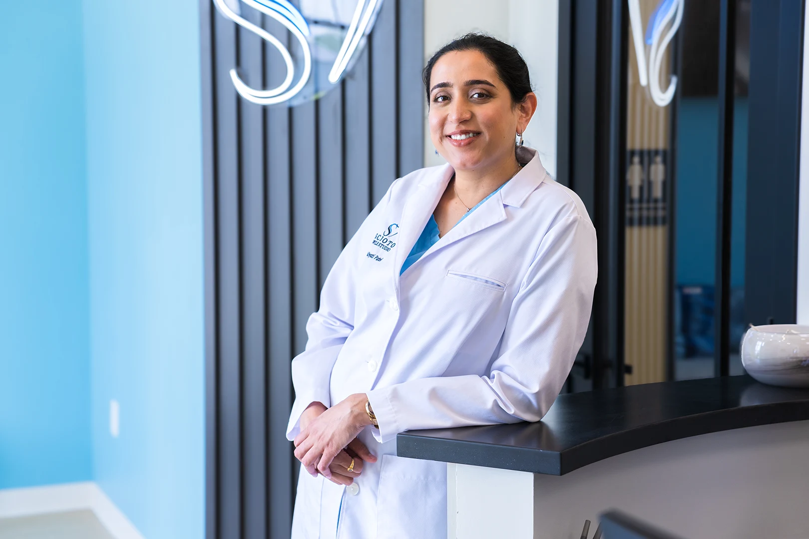 Dr. Khyati Patel standing at the reception of Scioto Smile Studio, warmly smiling